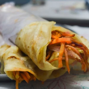 Veg masala roll cut in half showing crispy filling on a dark background - Seohara Kitchen