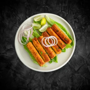 Plate of fried chicken seekh kebabs served with onion rings and lemon slices on a dark background - Seohara Kitchen