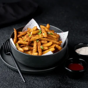 Crispy french fries tossed in red spicy peri-peri masala served on a black background - Seohara Kitchen
